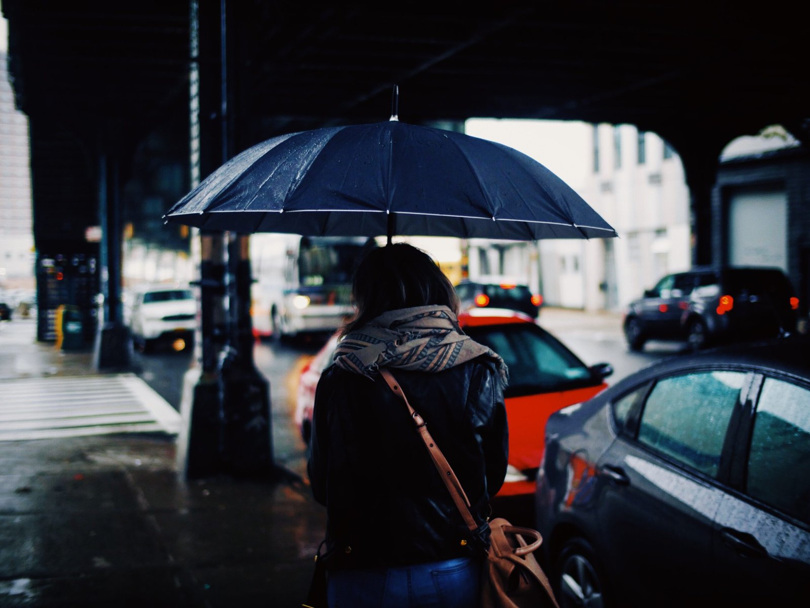 Pessoa caminhando na rua com guarda-chuva durante chuva forte